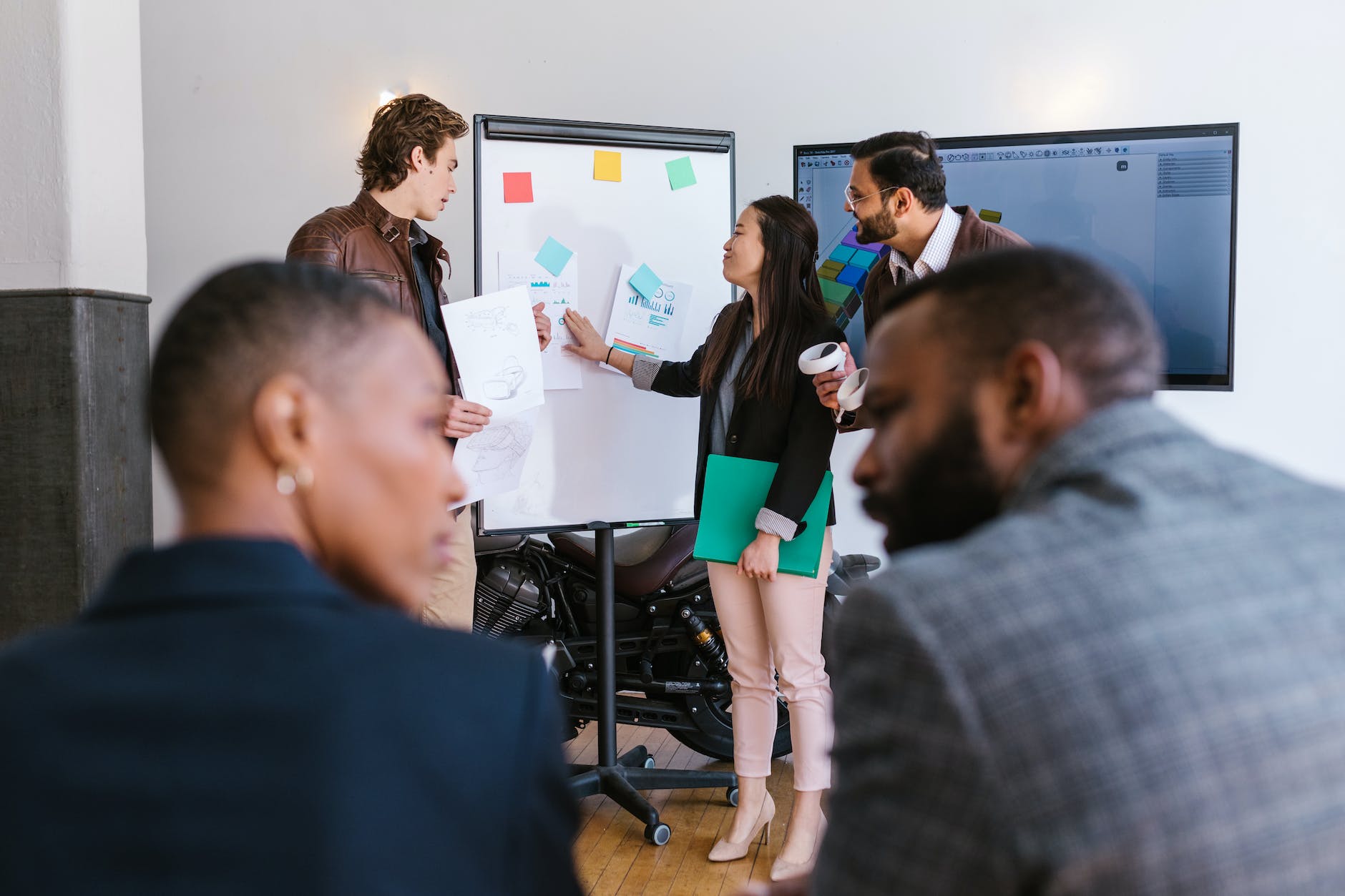 woman in black blazer holding green folder presenting a business proposal